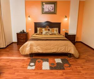 a bedroom with a large bed and a rug at Hotel Los Ilinizas in Latacunga