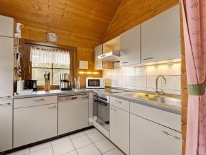 a kitchen with white cabinets and a wooden ceiling at Wooden holiday home in Hinterrod with sauna in Einsiedel