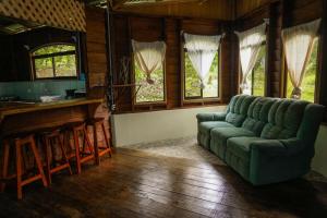 a living room with a green couch and a bar at Princesa de la Luna Ecolodge in Fortuna