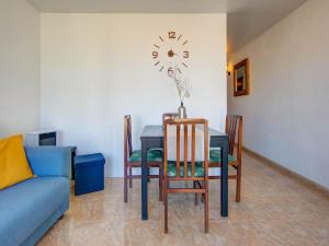 comedor con mesa y reloj en la pared en Belvilla by OYO Apartment in Lloret de Mar en Lloret de Mar