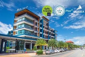 a building on the side of a street with palm trees at AVA SEA Ao Nang Beach Resort-SHA Extra Plus in Ao Nang Beach