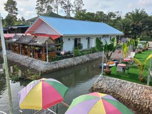 a house with umbrellas in front of a river at Boat house marina restaraunt and homestay in Surat Thani