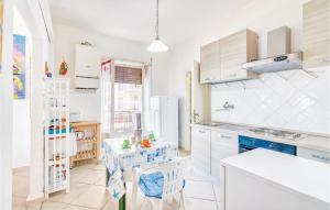 フォッローニカにあるNice Apartment In Follonica gr With 3 Bedrooms And Wifiの白いキャビネット、テーブルと椅子付きのキッチンが備わります。