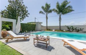 a swimming pool with two chairs and a table next to a pool at Beautiful Apartment In Comiso With 2 Bedrooms, Wifi And Outdoor Swimming Pool in Comiso