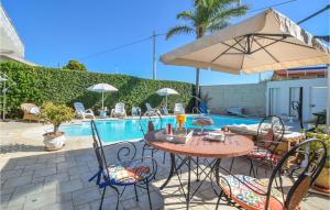 einen Tisch und Stühle mit einem Sonnenschirm neben einem Pool in der Unterkunft Villa Calambra in Villaggio Azzurro