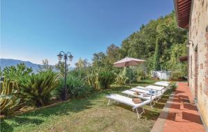 a row of white benches with an umbrella in a yard at Villa Marta Maria in Camaiore