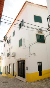 a white building with a yellow door on a street at Hotel A Cegonha in Alcácer do Sal