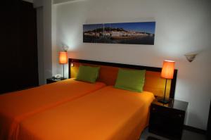 ein Schlafzimmer mit einem orangenen Bett mit zwei grünen Kissen in der Unterkunft Hotel A Cegonha in Alcácer do Sal