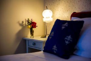 a table with a lamp and a vase of flowers on a bed at Ashdowns of Dover in Dover