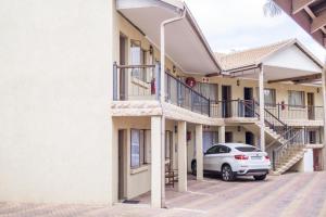 a car parked in a parking lot between two buildings at Ivory Lodge Bendor in Polokwane