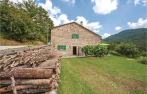 ein Steinhaus mit grünen Fenstern und einer Steinmauer in der Unterkunft Il Fienile in Badia Tedalda