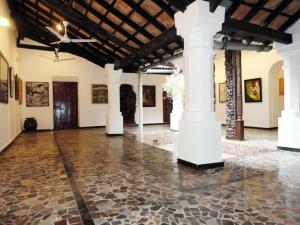 Habitación grande con columnas y cuadros en las paredes. en WelcomHeritage Panjim Pousada, en Panaji