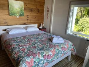a bedroom with a bed with a floral bedspread and a window at Tairua Treasure on Mount Paku in Tairua