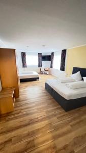a large bedroom with two beds and wooden floors at Hotel am Kirschberg in Alten Buseck
