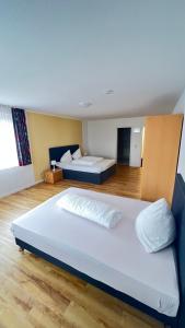 two beds in a large room with wooden floors at Hotel am Kirschberg in Alten Buseck