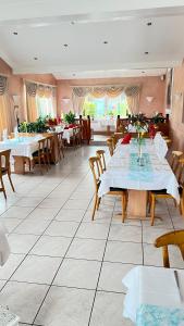 a restaurant with white tables and chairs and a room with tables at Hotel am Kirschberg in Alten Buseck