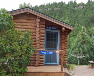 uma cabana de madeira com uma porta azul e um sinal em River Falls Lodging -Black Hills, South Dakota em Hot Springs