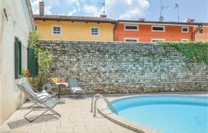 a swimming pool with two chairs and a stone wall at Casa Orange in Tissano