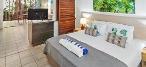 een slaapkamer met een groot bed met kussens erop bij REEF RETREAT APARTMENTS PALM COVE Unit 13 in Palm Cove