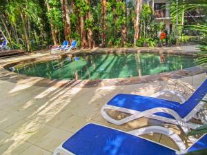 a swimming pool with a blue lounge chair next to it at REEF RETREAT APARTMENTS PALM COVE Unit 13 in Palm Cove