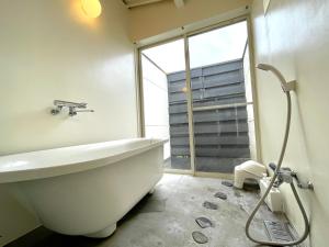 高松市にあるMegijima Beach Apartmentのバスルーム(バスタブ付)、窓が備わります。