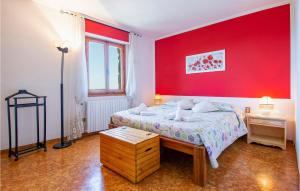 een slaapkamer met een rode muur met een bed en een tafel bij 2 Bedroom Pet Friendly Apartment In Lamporecchio in Lamporecchio