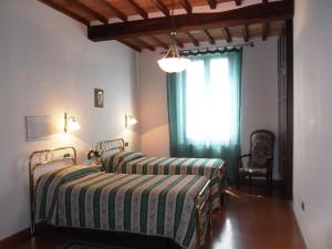 two beds in a room with a window and a chair at Palazzo Nanni in Montefalco