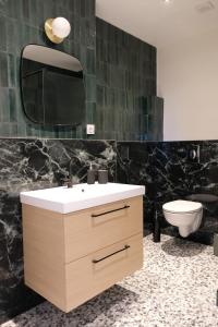 y baño con lavabo, espejo y aseo. en Emeraude, T2 design tout équipé Châteaucreux-Gare, en Saint-Étienne