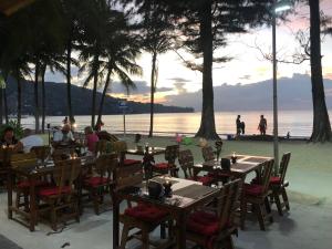 un ristorante sulla spiaggia con persone sedute ai tavoli di Deng's kamala beach Guesthouse a Kamala Beach