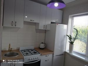 eine Küche mit weißen Schränken und einem Herd und einer Spüle in der Unterkunft Тіффані Апартаменти in Dnipro + 20 Fotos