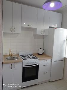 eine weiße Küche mit Herd und Spüle in der Unterkunft Тіффані Апартаменти in Dnipro