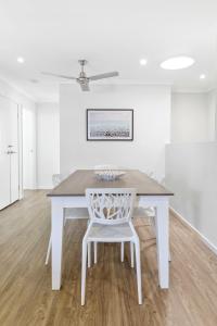 - une table à manger blanche avec une chaise blanche dans l'établissement 3BR, 3BTH, Walk to Beach & City Centre, à Maroochydore