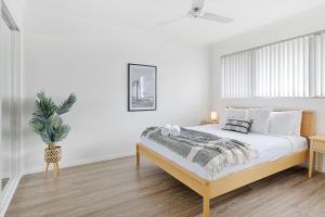 - une chambre blanche avec un lit et une plante en pot dans l'établissement 3BR, 3BTH, Walk to Beach & City Centre, à Maroochydore