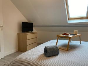 a bedroom with a bed with a table and a tv at Duplex moderne à 700m de la plage Parking & WiFi in Fort-Mahon-Plage