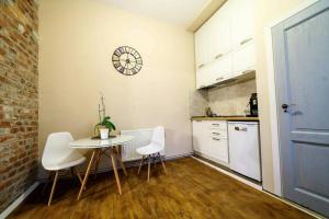 a kitchen with a table and chairs and a clock on the wall at Charming Apartment in Historical City Center in Timişoara