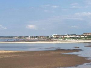 a beach with a group of people in the water at Troon Beach Town Golf Apartment Troon Ayrshire in Troon