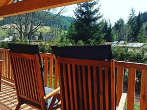two wooden chairs sitting on a deck with a view of the mountains at Natur-Camp Tannenfels in Baiersbronn +5 photos