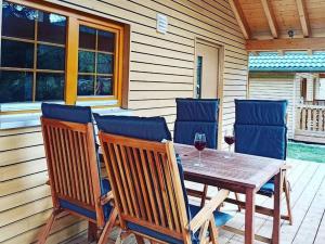 a wooden table and chairs on a porch with a glass of wine at Natur-Camp Tannenfels in Baiersbronn