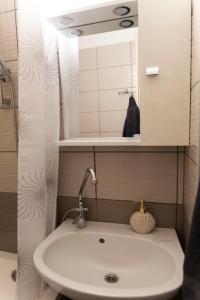 a bathroom with a sink and a mirror at Komló Szíve Apartman in Komló