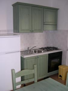 una cucina con armadi verdi, lavandino e piano cottura di Baia dei Canonici a Catanzaro Lido