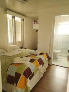 a bedroom with a bed and a bathroom with a toilet at Pousada Vale do Garimpeiro in Diamantina