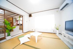 sala de estar con mesa y TV en Higashiomi Large House, en Higashiomi