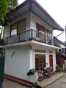 a motorcycle parked in front of a white house at Trinish homestay in Hatton