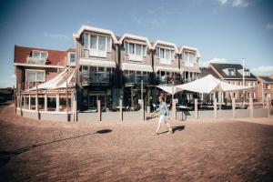 een persoon die voor een gebouw loopt bij Strandhotel Zoutelande in Zoutelande