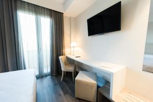 Habitación de hotel con escritorio y TV en la pared en Hotel Garden Experience, en Città di Castello
