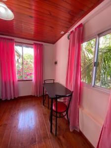 a dining room with pink curtains and a table and chairs at Mandua in Puerto Iguazú