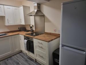 a kitchen with white cabinets and a stainless steel refrigerator at Impeccable Beachfront 2-Bed Cottage in St Bees in St Bees