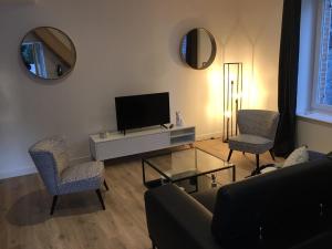 uma sala de estar com um sofá e duas cadeiras e uma televisão em Gîte Le Relais em Mer