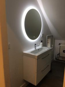 uma casa de banho com um lavatório e um espelho redondo em Gîte Le Relais em Mer