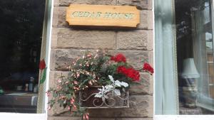 a sign on a brick wall with a potted plant at Cedar House B&B in Matlock